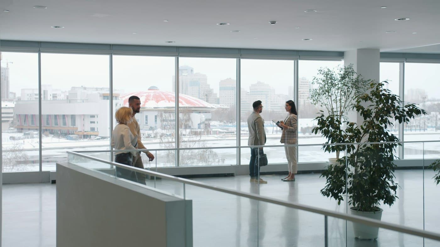 Colleagues talking beside the windows of a bright office.