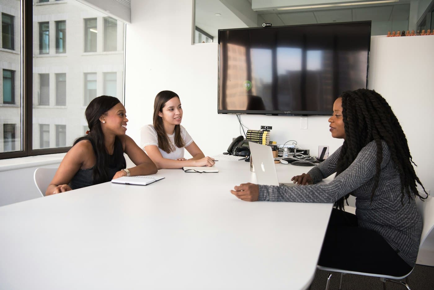 Three colleagues in a meeting around a conference table.